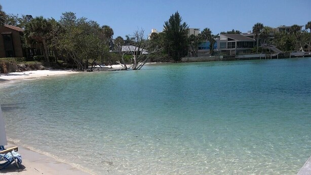 A clear beachfront with a sandy shore and a calm blue sea.