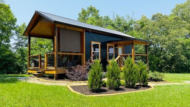 A wooden cabin with a porch, surrounded by a well-maintained garden. - Couple's Retreat: HotTub-FirePit-Grill-Pets-Wifi (Sevierville)