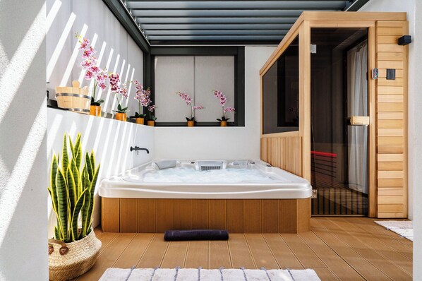 A spa area with a hot tub, wooden flooring, and potted plants.