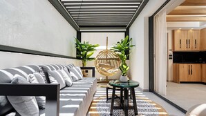 Una sala moderna con un sofá, una mesa redonda y una silla colgante. Se ve una cocina a través de una puerta abierta.