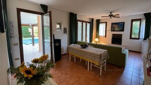 A room with a bed, a table, a ceiling fan, a TV, and a view of the outside. - Charming Villa With Pool in Albarella (Rosolina)