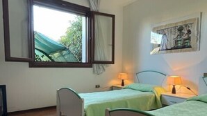 A room with two beds, a window with curtains, a wall-mounted picture, and tiled flooring. - Charming Villa With Pool in Albarella (Rosolina)