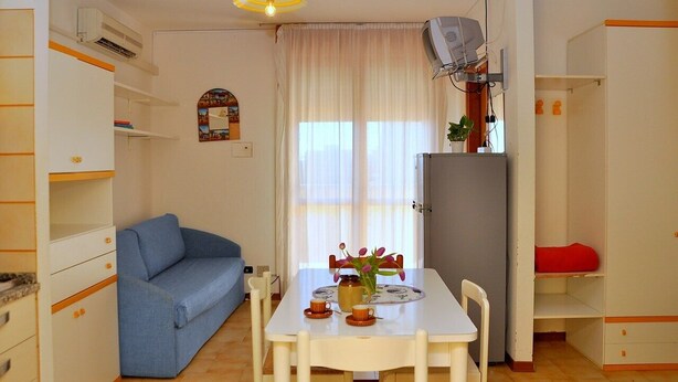 Un espacio habitable compacto con una mesa de comedor, un sofá azul y una pequeña cocina.