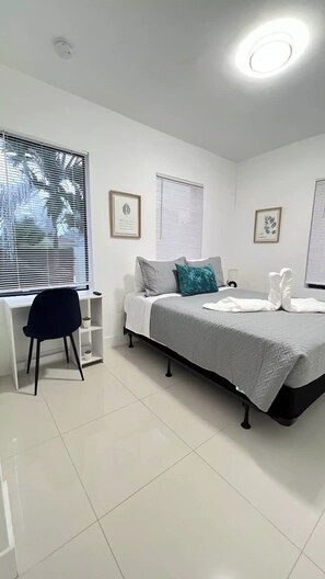 A modern bedroom with a bed, a desk, and a chair. - Stanza Design District Parking Laundry  (Miami)