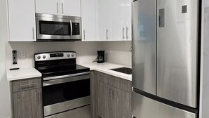 Uma cozinha moderna com eletrodomésticos de aço inoxidável, armários brancos e piso revestido.