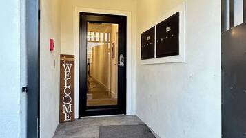 Corredor com placa de boas-vindas, uma porta e um painel de segurança.