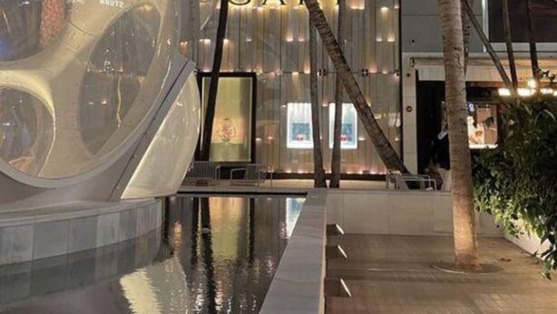 Um edifício moderno com fachada espelhada e área de piscina.