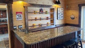 Eine Bar mit einer Granit-Arbeitsplatte, Holzregalen und zwei Pendelleuchten.
