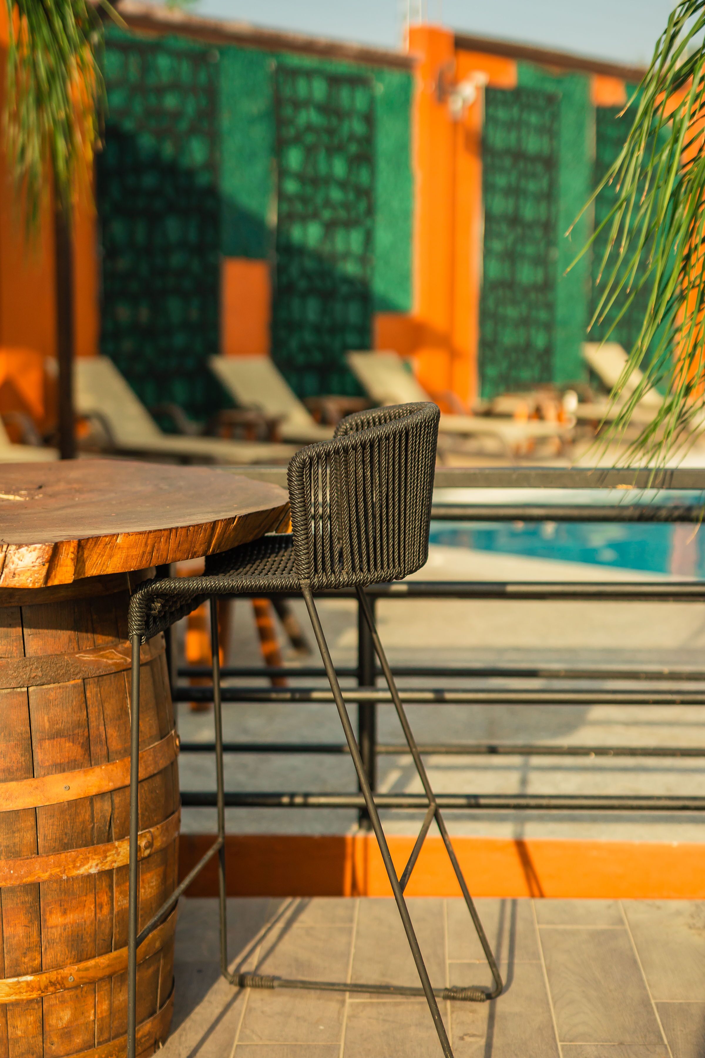A poolside bar area with a wooden table and a wicker chair.