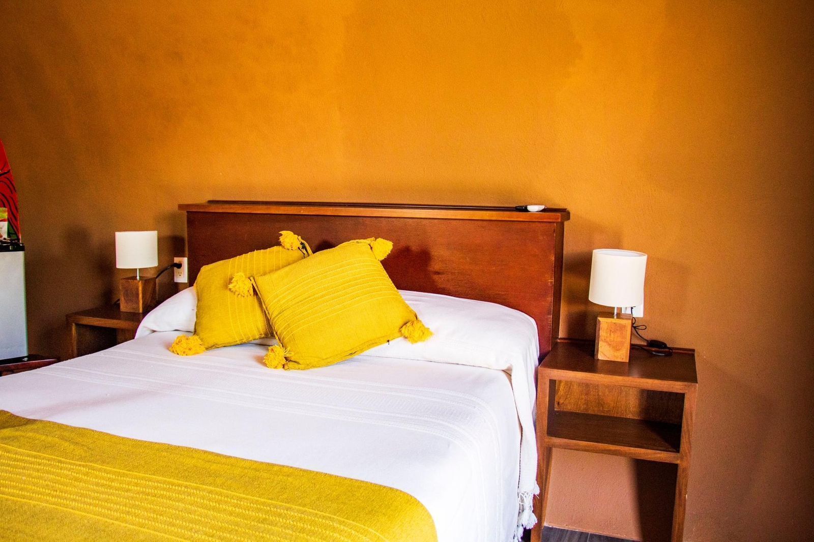 A hotel room with a large bed, two bedside tables with lamps, and a wooden headboard.