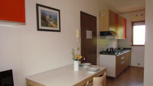 A compact living space with a dining area, kitchenette, and a TV on a small table. - Sporty Residence With all you Need (San Michele al Tagliamento)