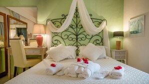 Uma cama bem arrumada com lençóis brancos e almofadas decorativas, uma mesa de cabeceira com abajur, e uma cadeira em um quarto com paredes verdes.