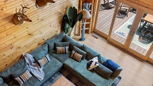 Puisesti sisustettu tila, jossa on sohva, tyynyjä, lamppu ja peuranpääaiheisia koristeita.