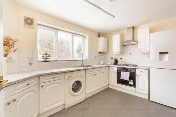 Compact kitchen with a functional layout, featuring a washing machine, stove, and sink, all integrated into a single unit.