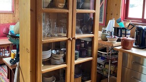 Ein Holzschrank mit Glastüren, der Geschirr und Gläser beherbergt.