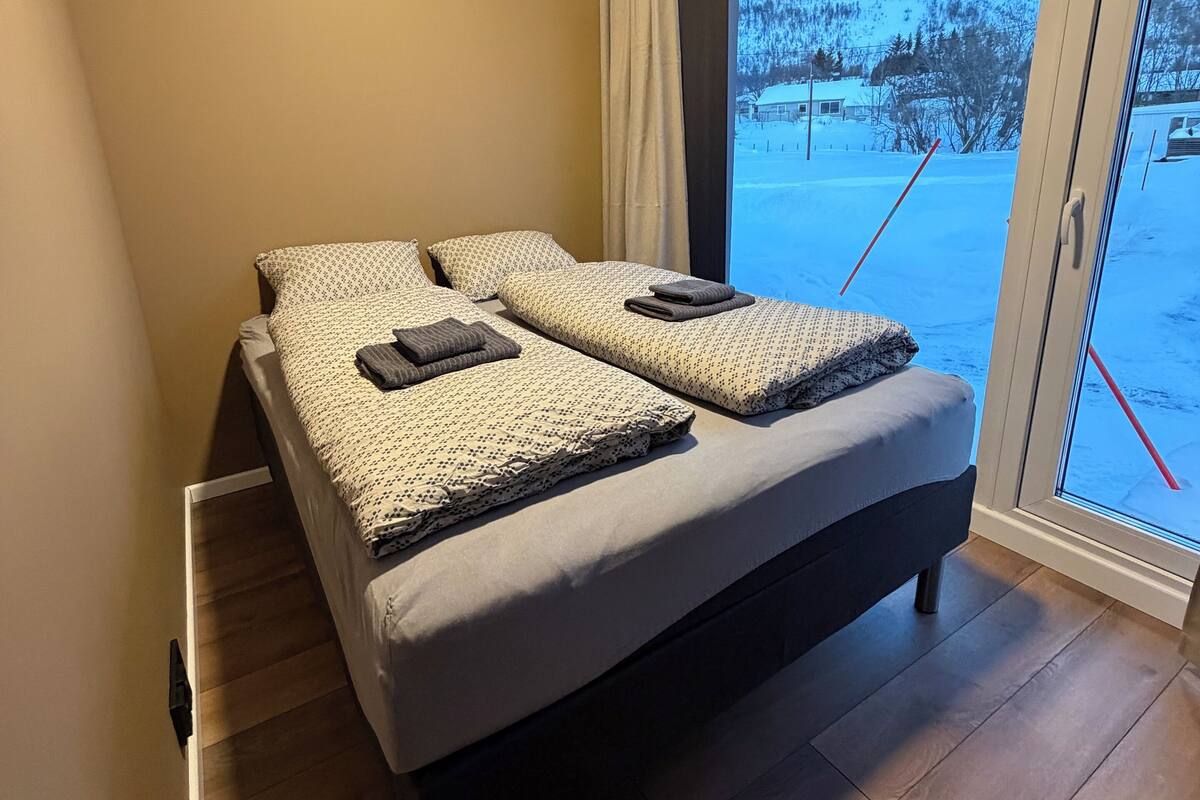 Un dormitorio con cama, ventana y vistas a un paisaje nevado.