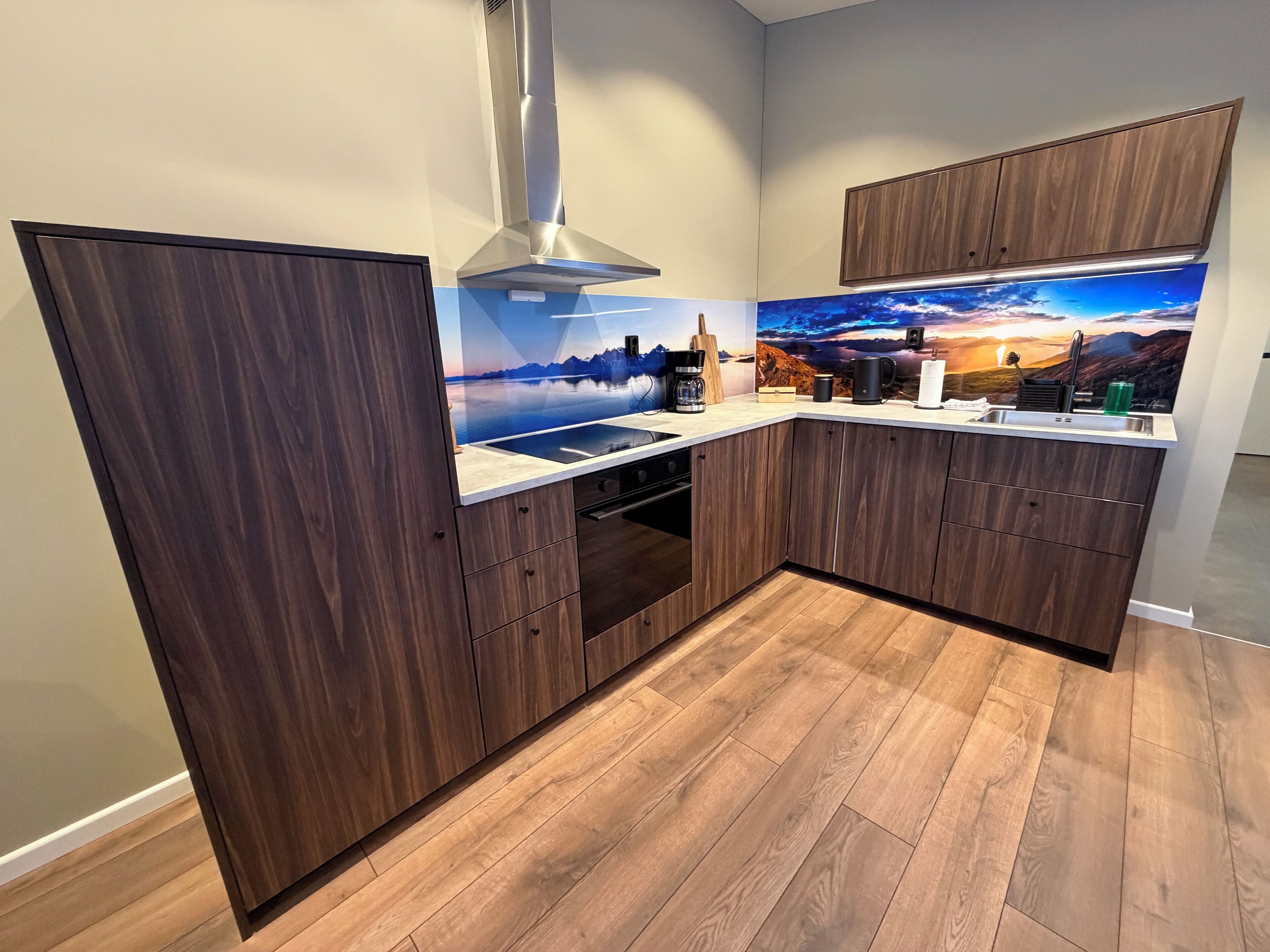 Een moderne keuken met houten kastjes, een roestvrijstalen afzuigkap en een sfeervol behang.