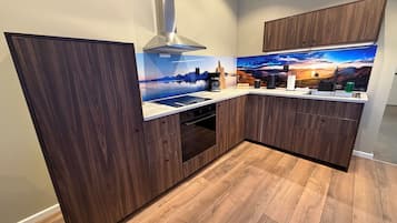 Een moderne keuken met houten kastjes, een roestvrijstalen afzuigkap en een sfeervol behang.