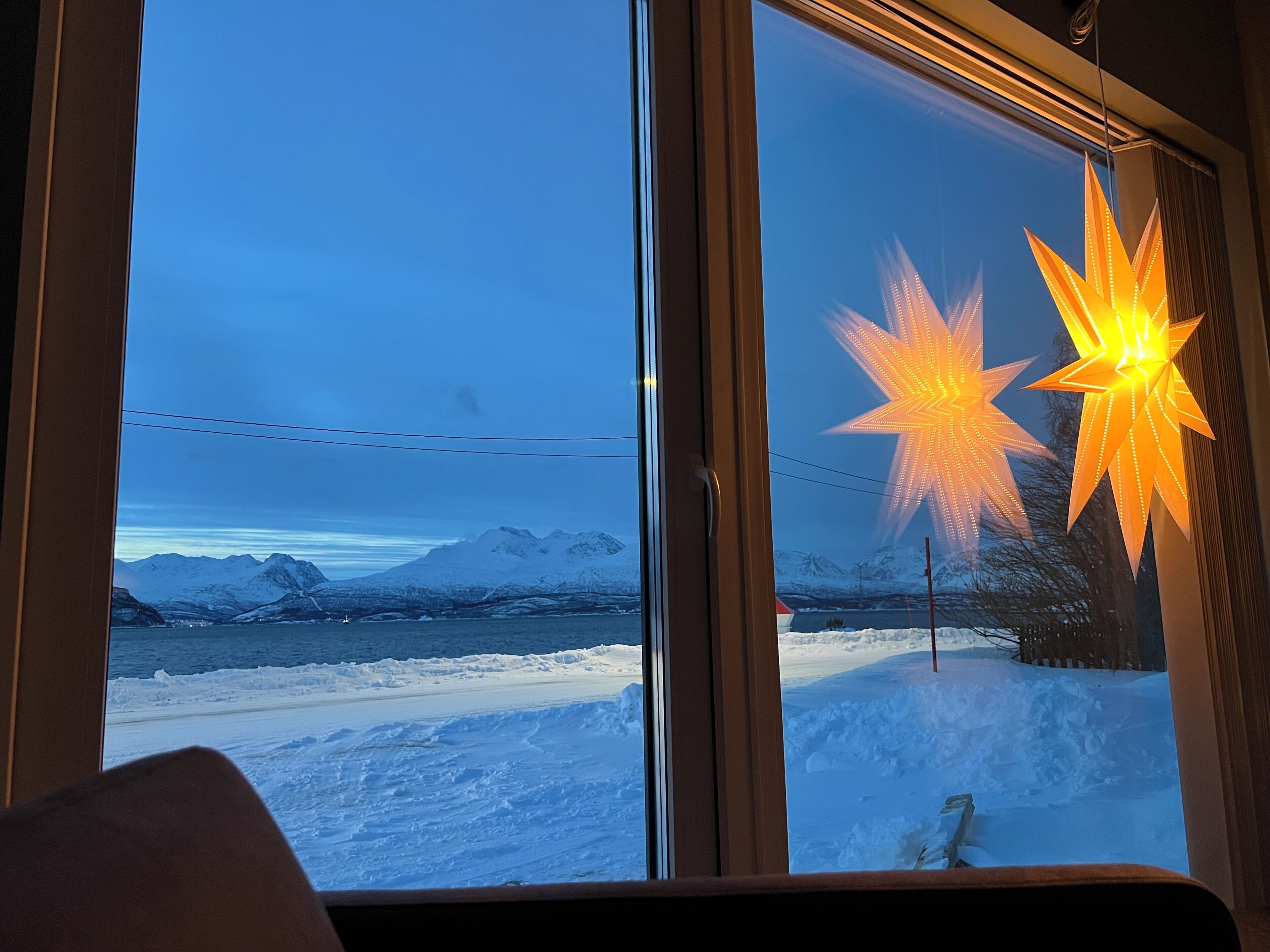 Una stanza con un'ampia finestra che si affaccia su un paesaggio innevato e montagne.