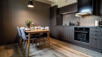 Una cucina moderna con mobili in legno scuro, forno integrato e zona pranzo con tavolo e sedie in legno.