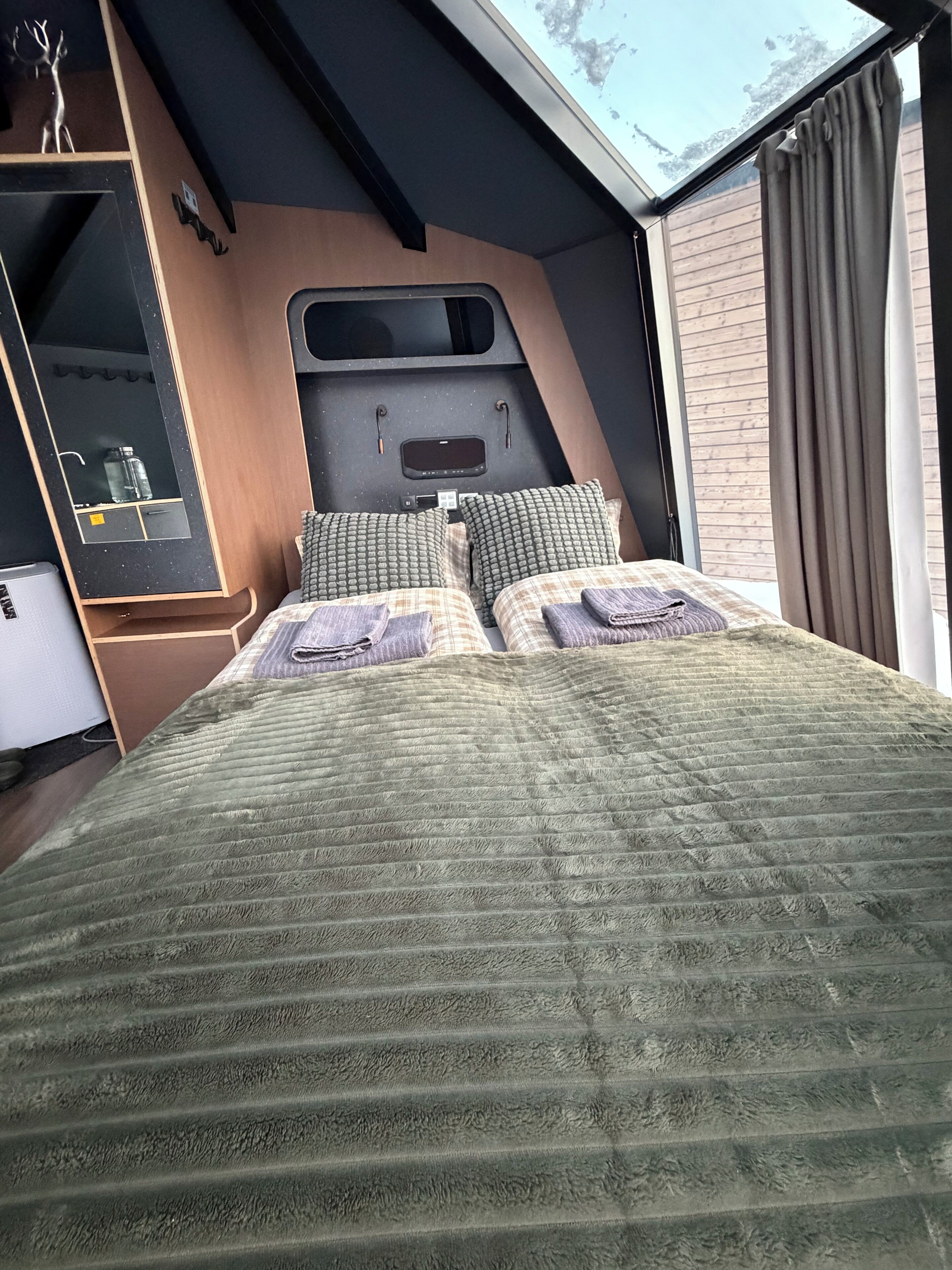 Ein Schlafzimmer mit einem Bett, einem Schminktisch, einem Spiegel und einem Fenster mit Vorhängen.
