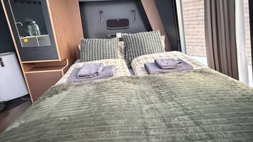 Ein Schlafzimmer mit einem Bett, einem Schminktisch, einem Spiegel und einem Fenster mit Vorhängen.