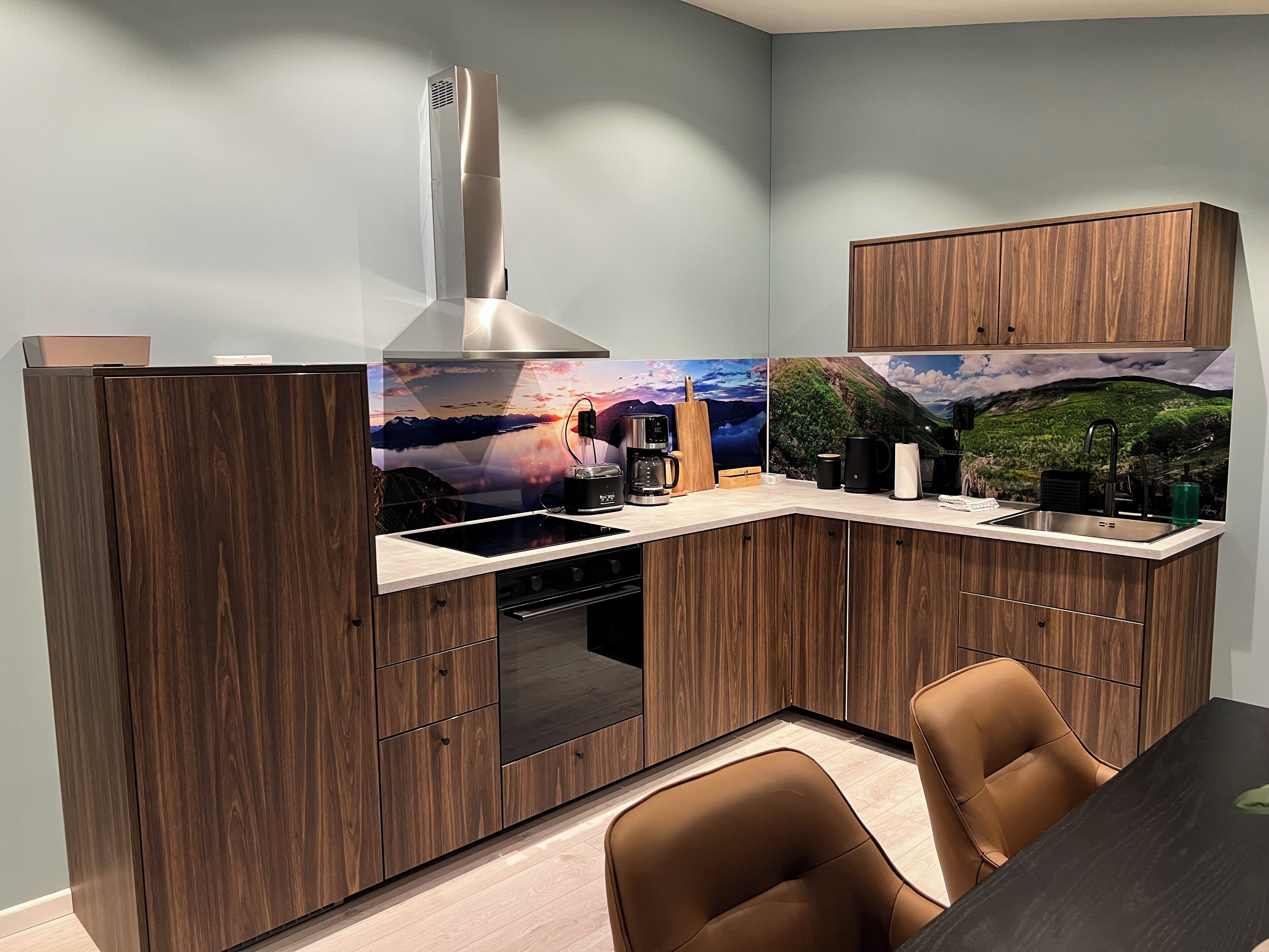 A compact kitchen with wooden cabinetry, a built-in stove, and a dining area with two chairs.