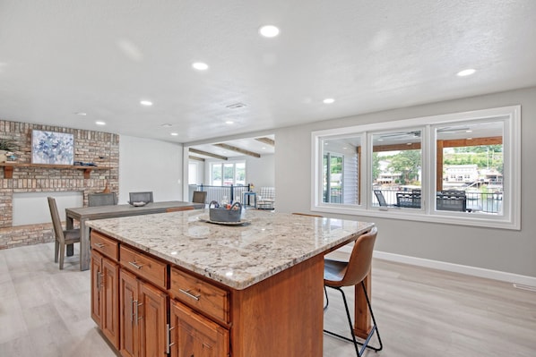 A spacious kitchen with a large island, wooden cabinets, and a stone backsplash.