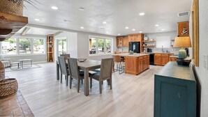 Une cuisine spacieuse dotée de meubles en bois, d’un îlot central et d’un coin repas avec une grande table et des chaises.