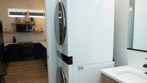 A compact kitchen with a built-in washer and dryer, a wooden cabinet, and a modern light fixture. - Mini Cottage Rentals, Monroe UT. Come Ride the trails (Monroe)