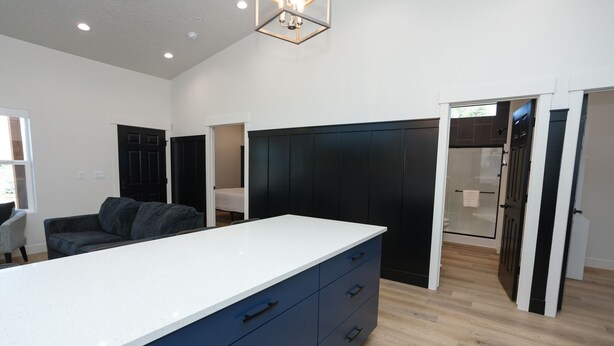 A modern kitchen with a large island, dark cabinetry, and a glass shower enclosure. - Mini Cottage Rentals, Monroe UT. Come Ride the trails (Monroe)