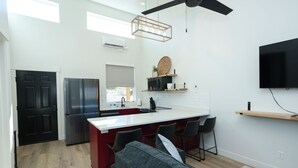 A modern kitchen with a central island, a dining area with a sofa, and a flat-screen TV mounted on the wall. - Mini Cottage Rentals, Monroe UT. Come Ride the trails (Monroe)