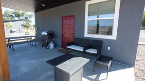 An outdoor patio area with a grill, seating, and a large window. - Mini Cottage Rentals, Monroe UT. Come Ride the trails (Monroe)