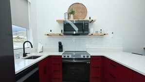 A modern kitchen with a stainless steel stove, red cabinets, and a white countertop. - Mini Cottage Rentals, Monroe UT. Come Ride the trails (Monroe)