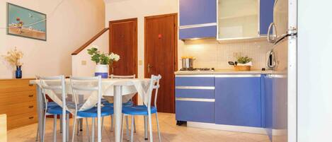Una cocina con una mesa de comedor, sillas, armarios y un refrigerador.