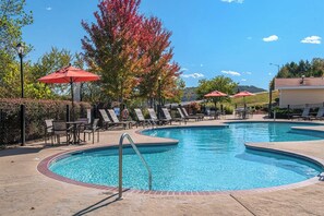 Relax by the pool surrounded by lush trees and comfortable lounge chairs.