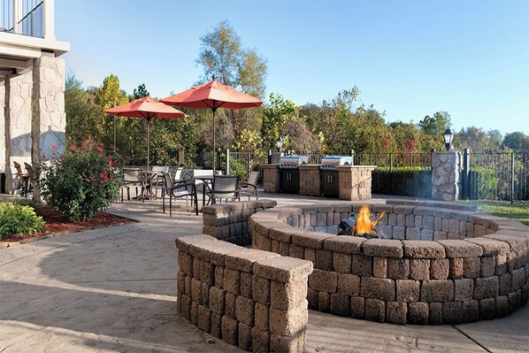 Enjoy al fresco dining and relaxation in this beautifully landscaped patio area, featuring a fire pit, grill, and comfortable seating.