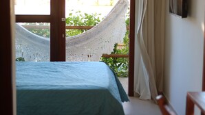 Una habitación con cama, una hamaca y vistas al verde exterior.
