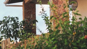 A modern building with stone pillars, a wooden roof, and a hanging light fixture. - Pousada Casa de Hóspedes (Amontada)
