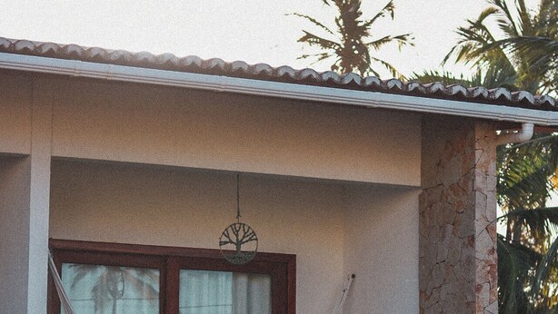 A house with a large window, a wooden fence, and a tree in the background. - Pousada Casa de Hóspedes (Amontada)