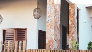 Un edificio con una columna de piedra, contraventanas de madera y una lámpara colgante.