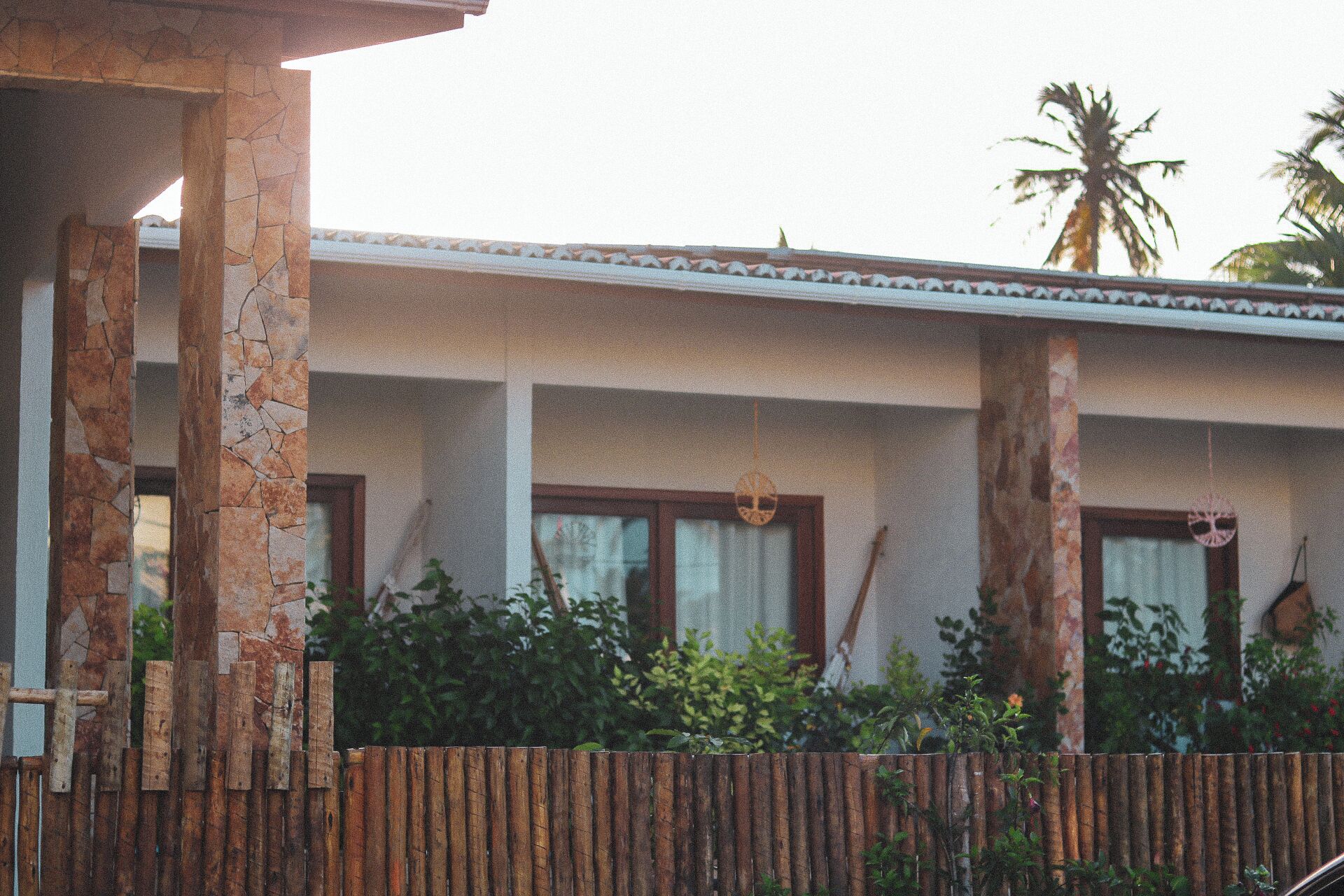 A building with stone pillars, wooden fence, and a tiled roof.
