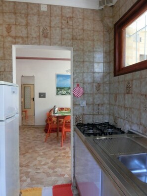 A kitchen with a gas stove, a sink, and a dining area with a table and chairs.