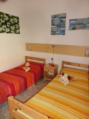 Ein Zimmer mit zwei Einzelbetten, einem Nachttisch und einer Wand mit Bildern.