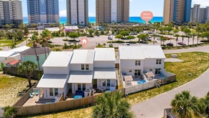 Una propiedad frente a la playa con varios edificios blancos, una zona de piscina y vistas al océano.
