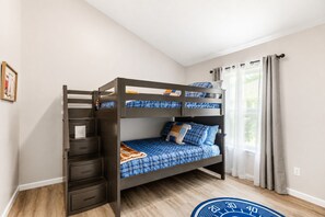 A bunk bed with drawers, a window with curtains, and a blue circular rug. - 2 Homes Side by Side, Families and Groups Welcome!  Sleeps up to 16 & Courtyard. (St. Augustine)