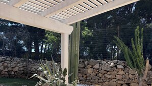 Ulkoterassi, jossa on pergola, kiviseinät ja kaktuksia.