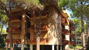 Un edificio de varios pisos con balcones, rodeado de árboles.