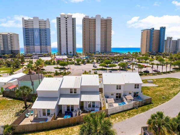 A beachfront property with multiple white buildings, a swimming pool, and a view of the ocean.