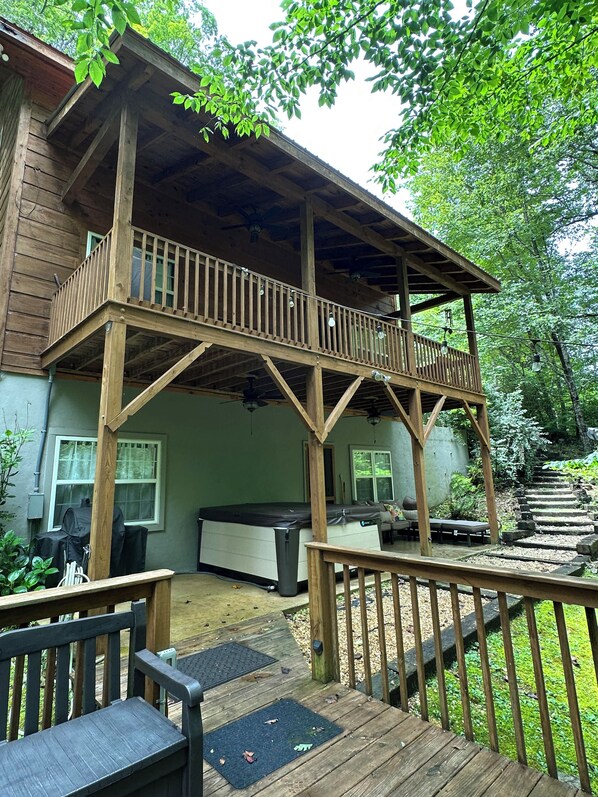 A wooden deck with a balcony, a hot tub, and a covered seating area. - Creekside, Pet Friendly Mountain Log Cabin in the Smokies,  Fire Pit + Hot Tub  (Franklin)
